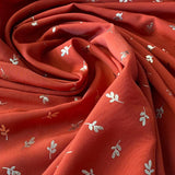 Oranžs poliesters ar ziedlapiņu apdruku